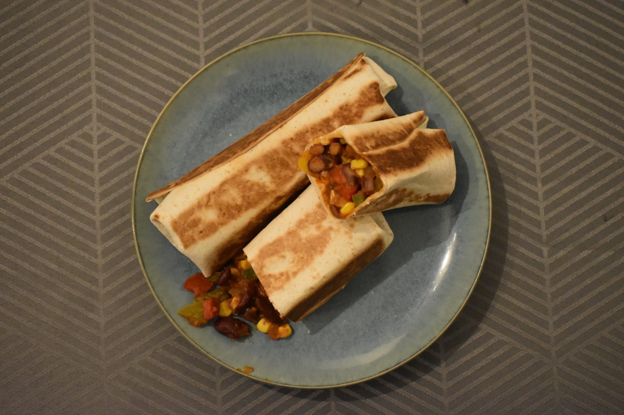 Pasta met stukjes chorizo en groenten in een zwarte kom.